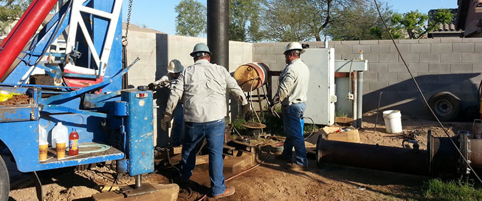 two workers operating a drilling rig for well installation