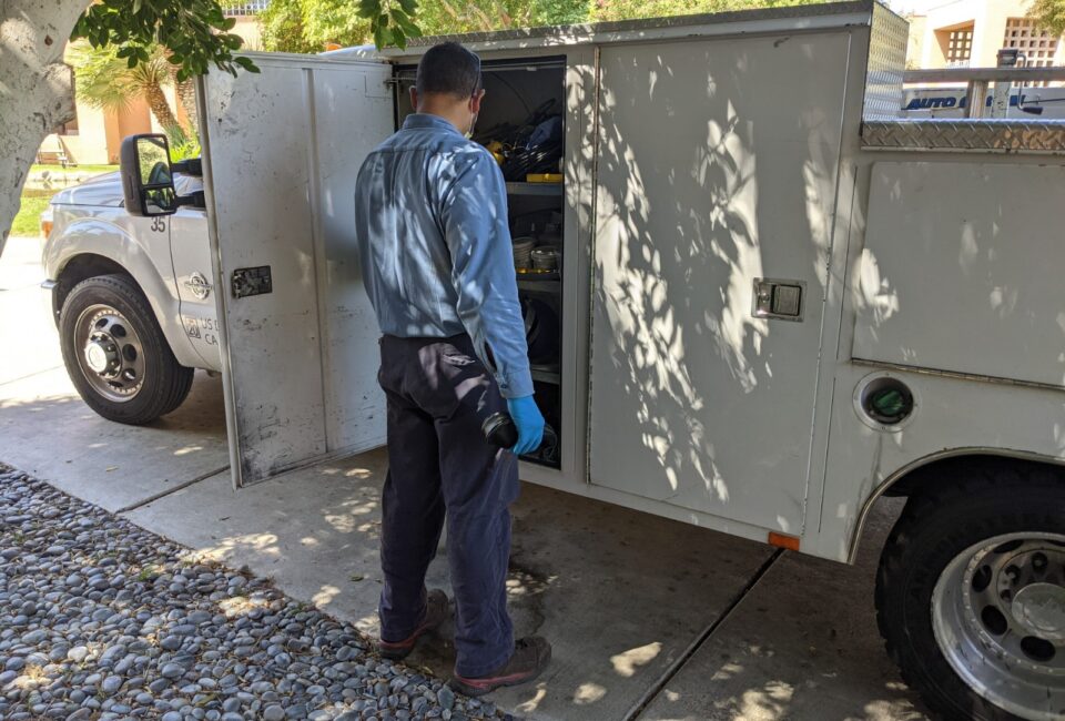 technician by the service truck, used for plumbing or HVAC repairs